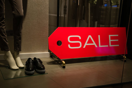 Red sale in shopping window of fashion store and woman passing, sales conceptの写真素材