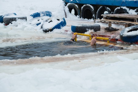 man dived into the hole on the feast of baptism, Orthodox tradition, Man bathing in the ice cold water. The Epiphany, celebrated on jan 19の写真素材