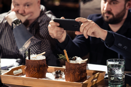 man photographing a cocktail in a bar on a smartphone, February 6th Bartender's Day Minsk, toned, Belarus, 2019のeditorial素材