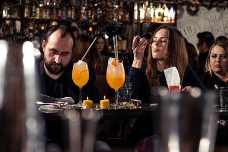 Cocktail bars, competition of bartenders, a jury of a girl and a man tasting a new alcoholic cocktail February 6th Bartender's Day Minsk, toned, Belarus, 2019のeditorial素材
