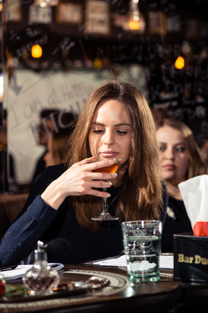 Cocktail bars, competition of bartenders, a jury of a girl and a man tasting a new alcoholic cocktail February 6th Bartender's Day Minsk, toned, Belarus, 2019のeditorial素材