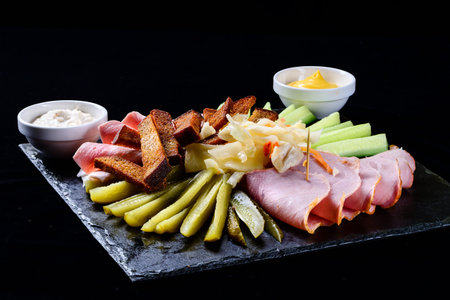 set of salami snacks, ham, sausage and fermented cucumbers on a dark backgroundの写真素材