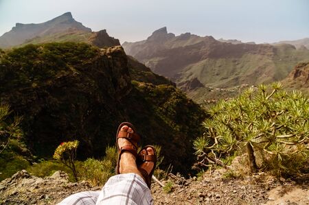Legs of traveler sitting on a high mountain top in travel. Freedom concept. Hiker in Anaga Mountains, Tenerife, Canary Islands, Spainの写真素材