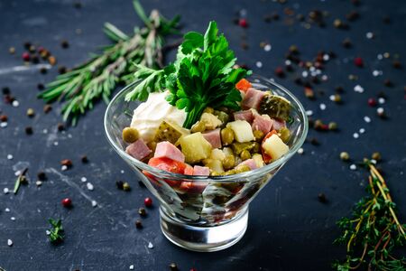 Bowl of traditional russian salad "Olivier" from boiled vegetables and sausage with mayonnaise. Russian New Year or Christmas salad on wooden Rustic backgroundの写真素材