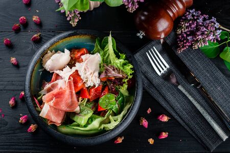 Fresh salad - Delicious fresh salad with parma prosciutto ham, arugula and Parmesan. Black background, top view.の写真素材
