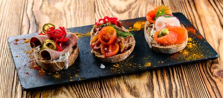 set of many different bruschettas at wooden table top. italian cuisine appetizer with many ingridientsの写真素材