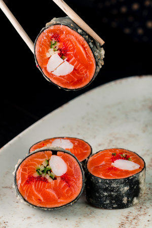 Sushi rolls with salmon on sticks close up, sushi maki with chop sticks verticallyの写真素材
