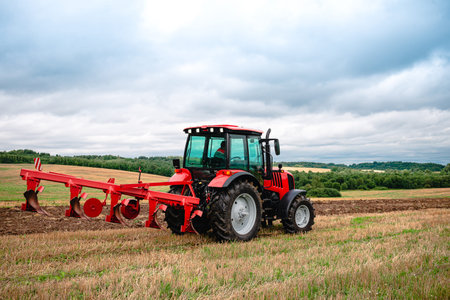 Tractor with plow, Small scale farming with tractor and plow in field. Heavy agricultural machinery...