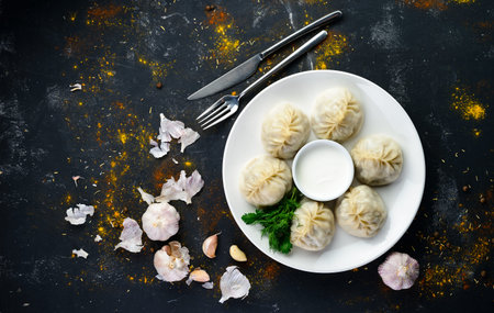 Georgian dumplings Khinkali with meat, greens and tomato spicy sauce Satsebeli on white plate top...