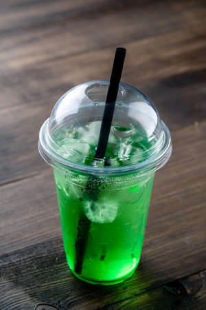 Mojito and Lemonade summer cold drink in a plastic glass with a straw. Coctail Beverage closeup green lemonade with ice in a plastic takeaway glassの写真素材