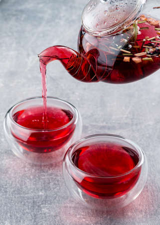 red tea is poured from a teapot into a bowl, raspberry tea with fresh berriesの写真素材