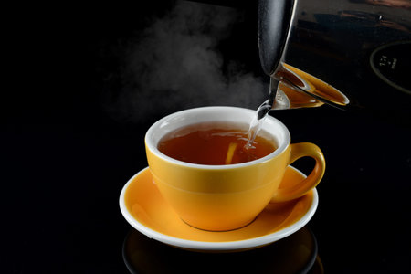 cup of hot tea with lemon and steam, hot tea with lemon on a black background with copy space for textの写真素材
