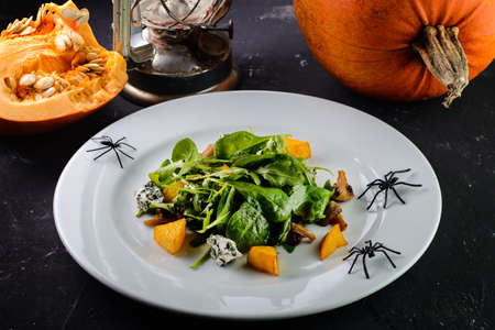 Salad for Halloween holiday on table. Pumpkin Gloomy atmosphere on dark background. Vegetarian healthy food on woodenの写真素材