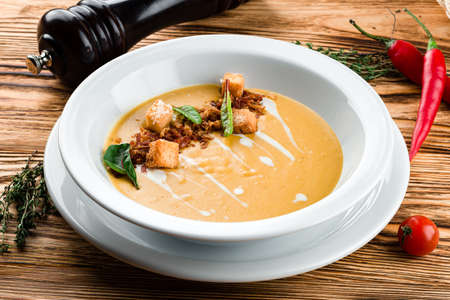 Pumpkin soup in white plate on wooden backgroundの写真素材