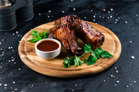 Hot grilled and smoked spare ribs. BBQ served on a round wooden cutting board, grilled ribsの写真素材