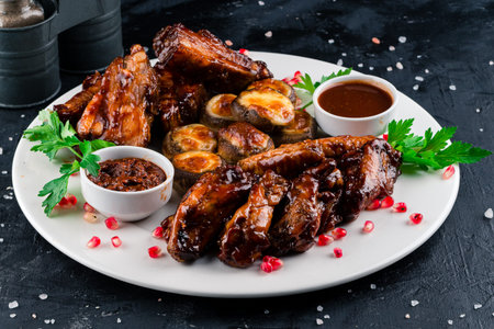 Mixed grilled meat Juicy barbecue pork ribs and dry chicken wings on dark background, grilled...