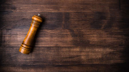 Mill for pepper, wooden pepper pot on a brown wooden table with free space for text. Top view. Free space for your text, with copy space backgroundの写真素材