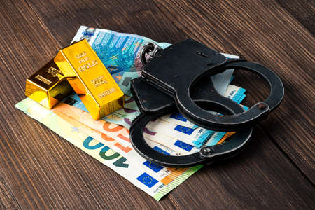 Gold bullions with handcuffs on euro banknotes, financial concept of handcuffs and gold bars on Euro banknotesの写真素材