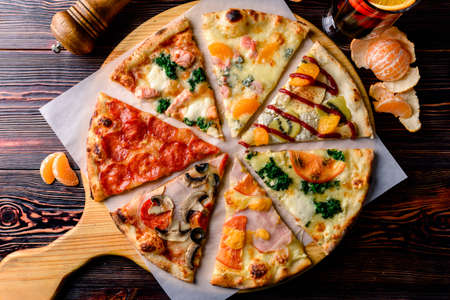 different pizza slices on a wooden table, mix of eight different pizzas on a wooden background. menu concept of choice and diversityの写真素材