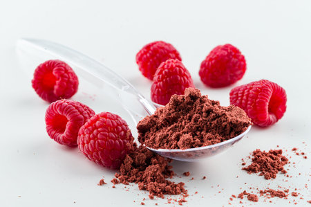 A pile of instant raspberry juice powder concentrate on a white background. dry raspberry super food...