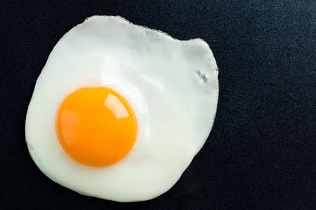 fried egg in a frying pan, Close up view of the fried eggs on blackの写真素材
