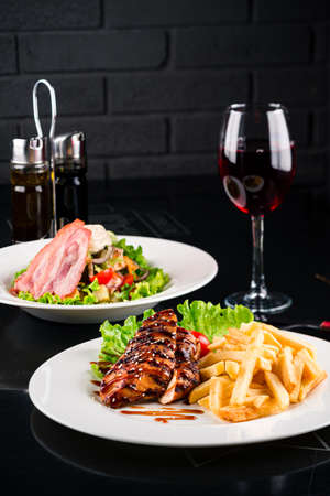 Fried chicken fillet, French fries and vegetables. grilled chicken fillet and french fries with saladの写真素材