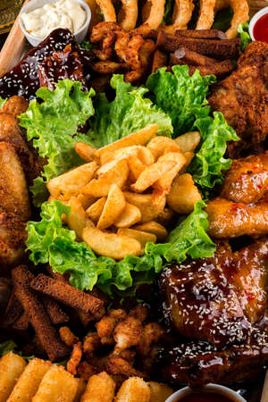 fat junk food close-up. fast food and unhealthy eating concept of fast food snacks on wooden tableの写真素材