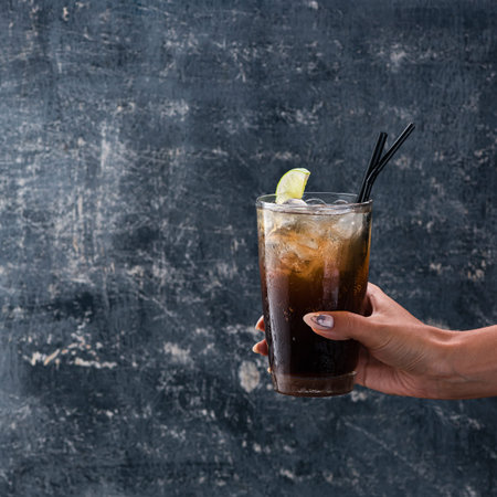 hand of girl holding glass of rum with cokeの写真素材