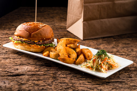 Fresh double burger and potato fries takeaway on wooden background. Food deliveryの写真素材