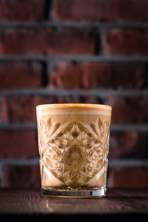 Flat white coffee in transparent glass on wooden table. It is espresso coffee with microfoam steamed milkの写真素材