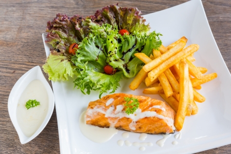 Salmon steak served with french fried and lettuceの写真素材