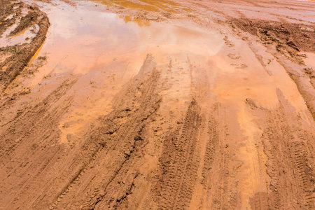 Wheel tracks on red color marshy road after raining