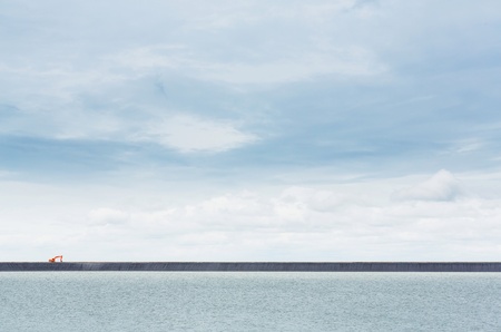 Orange color backhoe working on dam crestの写真素材