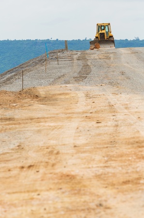 Yellow color backhoe working on dam crest の写真素材