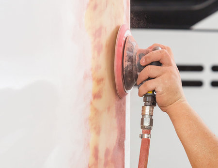 Workers polished putty on car by pneumatic sander machine