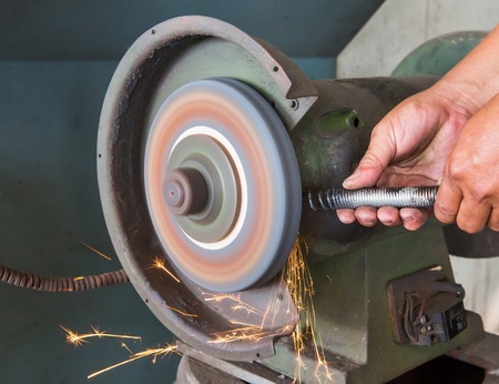 Worker using grinding wheel in car garageの写真素材