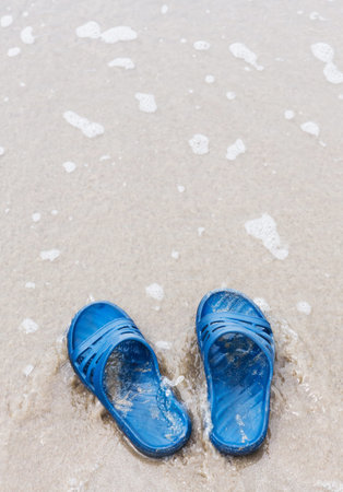 Close up blue color slippers on the beach for vacation or holiday concept