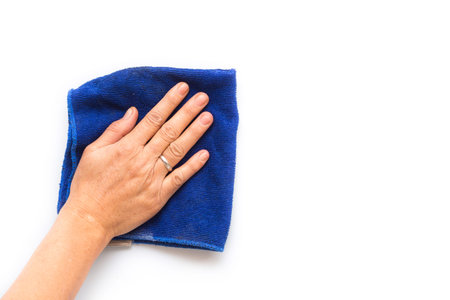 Close up hand with blue cloth cleaning on white wall