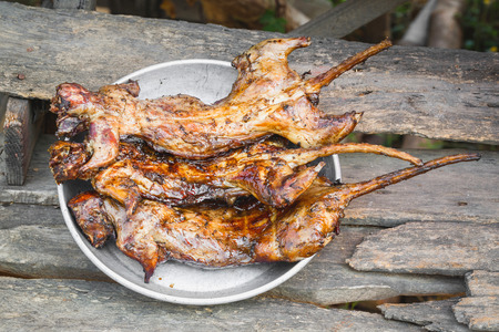 Close up grilled rice field rat on aluminum dish on old and dirty wooden table from central of Thailandの写真素材