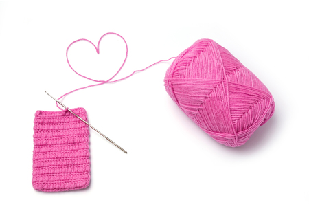 Close up unfinished pink color crochet pocket with heart symbol on knitting wool isolated on white - mean doing with loveの写真素材