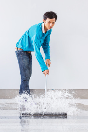 Asian worker using wiper or squeegee to clean floor surfaceの写真素材