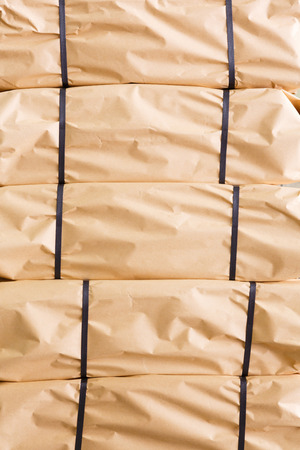 Stack of parcel wrapped in brown recycled paper and tied with PP strapping bandの写真素材