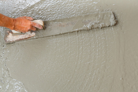 Close up worker hand using float to level surface of concreteの写真素材