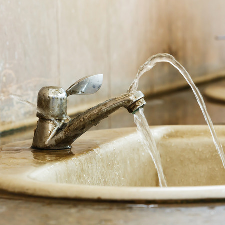 Close up leak and ruin valve in dirty old bathroomの写真素材