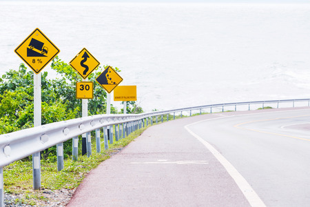 Signs on curves and slopes road beside the seaの写真素材