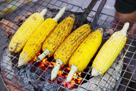 Close up charcoal grilled corn on clay stove, traditional cooking styleの写真素材
