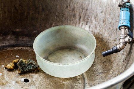Close up old and dirty water bowl in alunimium basinの写真素材