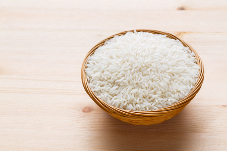 Close up Thai jasmine rice in wicker basket on wooden tableの写真素材