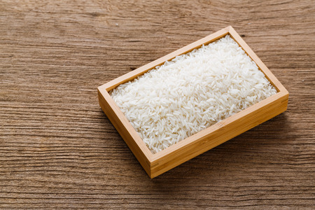 Close up Thai jasmine rice in wood tray or box on wooden tableの写真素材
