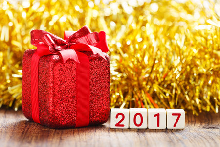 Happy new year 2017 with present on wooden table, red gift box with bow tie, seasonal celebration...